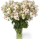 a bouquet of light pink flowers in a glass vase